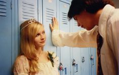 a man and woman standing in front of lockers with their hands on the wall