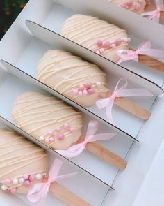 three desserts in boxes with pink ribbons and bows on them are ready to be eaten