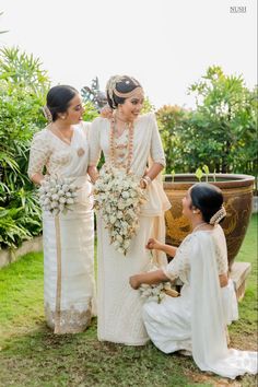 three women standing next to each other in white dresses