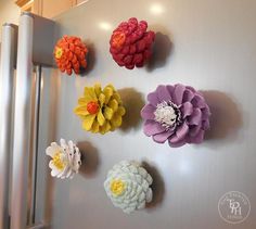 the refrigerator is decorated with colorful flowers on it's magnets, and they are hanging on the wall