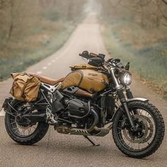 a motorcycle parked on the side of a road in the middle of the woods with luggage strapped to it's back