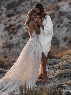 two women in white dresses standing next to each other on top of a hill together