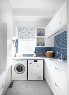 a washer and dryer in a small room with blue tile on the walls