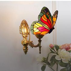 a lamp that is on the side of a wall next to a vase with flowers