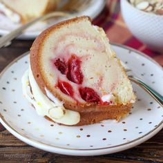 a piece of cake with strawberries on it sitting on a plate next to a fork