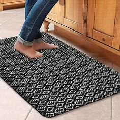 a person standing on a rug in the middle of a kitchen floor next to a sink