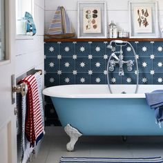 a bathroom with blue and white tiles on the walls, an old claw foot bathtub