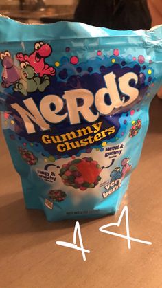 a bag of nerds gummy bears sitting on top of a counter next to a woman