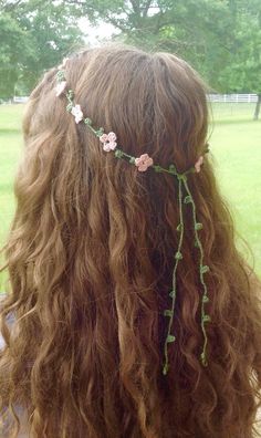 the back of a woman's head with long curly hair and flowers on it