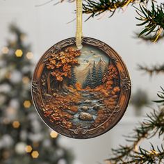 an ornament hanging from a christmas tree decorated with autumn trees and rocks in the water