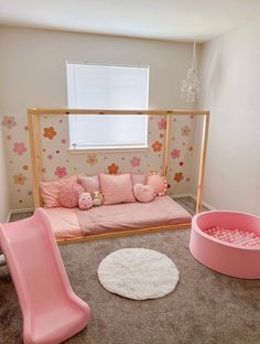 a room with pink furniture and flowers on the walls, carpeted flooring and rugs