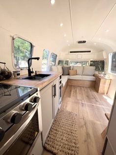 the interior of an rv with wood flooring and white walls, including a stove top oven