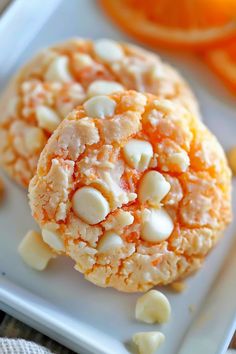 an orange and white cookie on a plate with some peeled oranges in the background