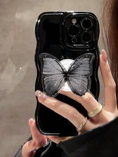 a woman holding up a phone case with a butterfly on it