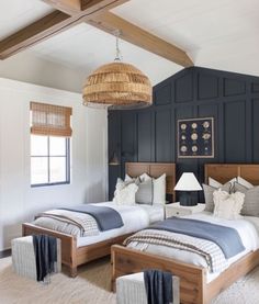 two twin beds in a bedroom with blue walls and wood beams on either side of the bed