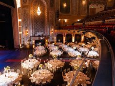 an empty stage with tables and chairs set up for a formal function in the center