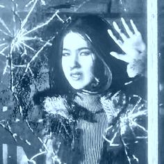 an old photo of a woman with her hands up in front of the camera and snowflakes behind her