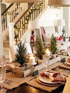 a table set for christmas with candles, plates and napkins on top of it