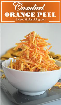 a white bowl filled with shredded orange peels on top of a metal serving tray