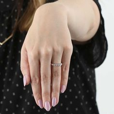 a woman's hand with a diamond ring on her left thumb and pink nail polish