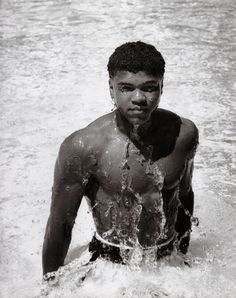 a young man sitting in the water with no shirt on