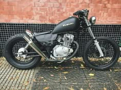 a black motorcycle parked in front of a brick wall