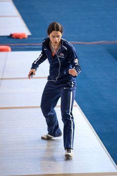 a woman in blue tracksuits and headphones is running on a track while listening to music