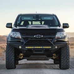 the front end of a black truck on a dirt road