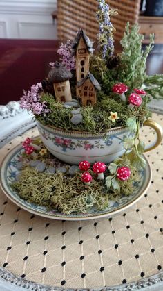 a teacup filled with moss and little houses