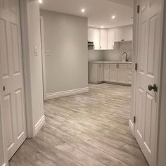 an empty room with white cabinets and wood floors