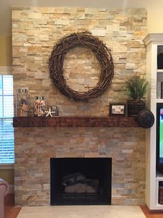 a stone fireplace with a wreath on the mantel and bookshelf behind it