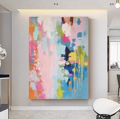 an abstract painting hangs on the wall above a dining room table