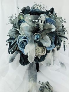 a bridal bouquet with blue and white flowers on the bottom, surrounded by silver accents