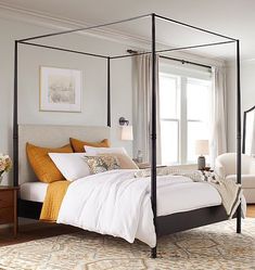 a bedroom with a four poster bed, white walls and beige carpeting on the floor