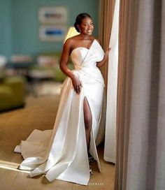 a woman in a white dress leaning against a curtain