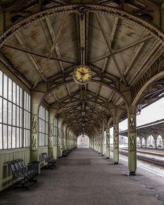 an empty train station with benches and a clock