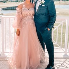 a man and woman standing next to each other in front of a white fence wearing formal wear