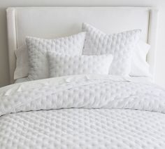 a bed with white sheets and pillows on it