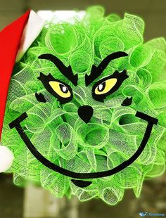 a close up of a person holding a green wreath with a face drawn on it