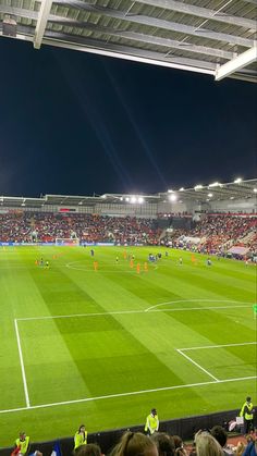 an empty soccer field at night with many people on the field and in the stands