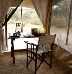 the inside of a tent with a table and chairs in front of an open window