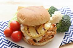 a chicken sandwich with broccoli, tomatoes and cauliflower on a plate