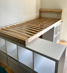 the bed frame is made from wood and has drawers underneath it, along with white cupboards