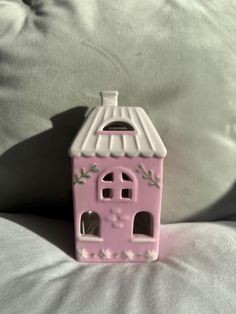 a small pink house sitting on top of a bed