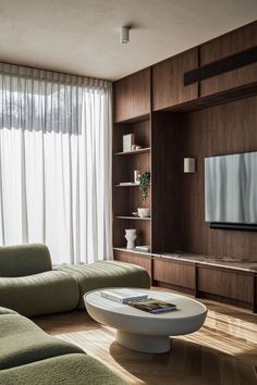 a living room filled with furniture and a flat screen tv mounted on a wall next to a window