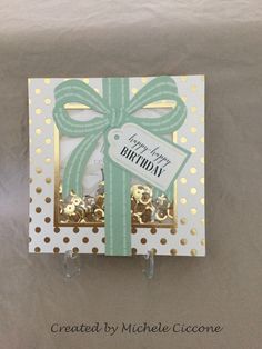 a birthday card with a green bow and gold confetti on it's side