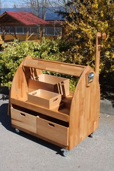 a wooden desk with drawers on wheels in front of bushes