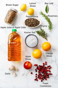 the ingredients to make an apple cider are displayed on a marble counter top, including oranges, lemons and spices