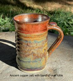 a brown and blue mug sitting on top of a rock