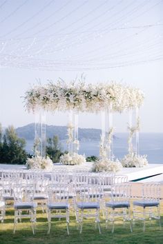 an outdoor wedding setup with white flowers and greenery on the aisle, overlooking the ocean